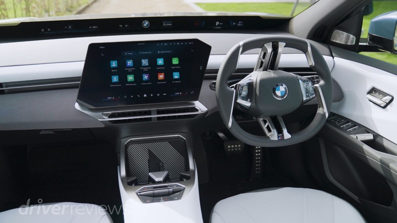 BMW iX3 interior with Panoramic iDrive screen showing BMW OS X app grid in light interior