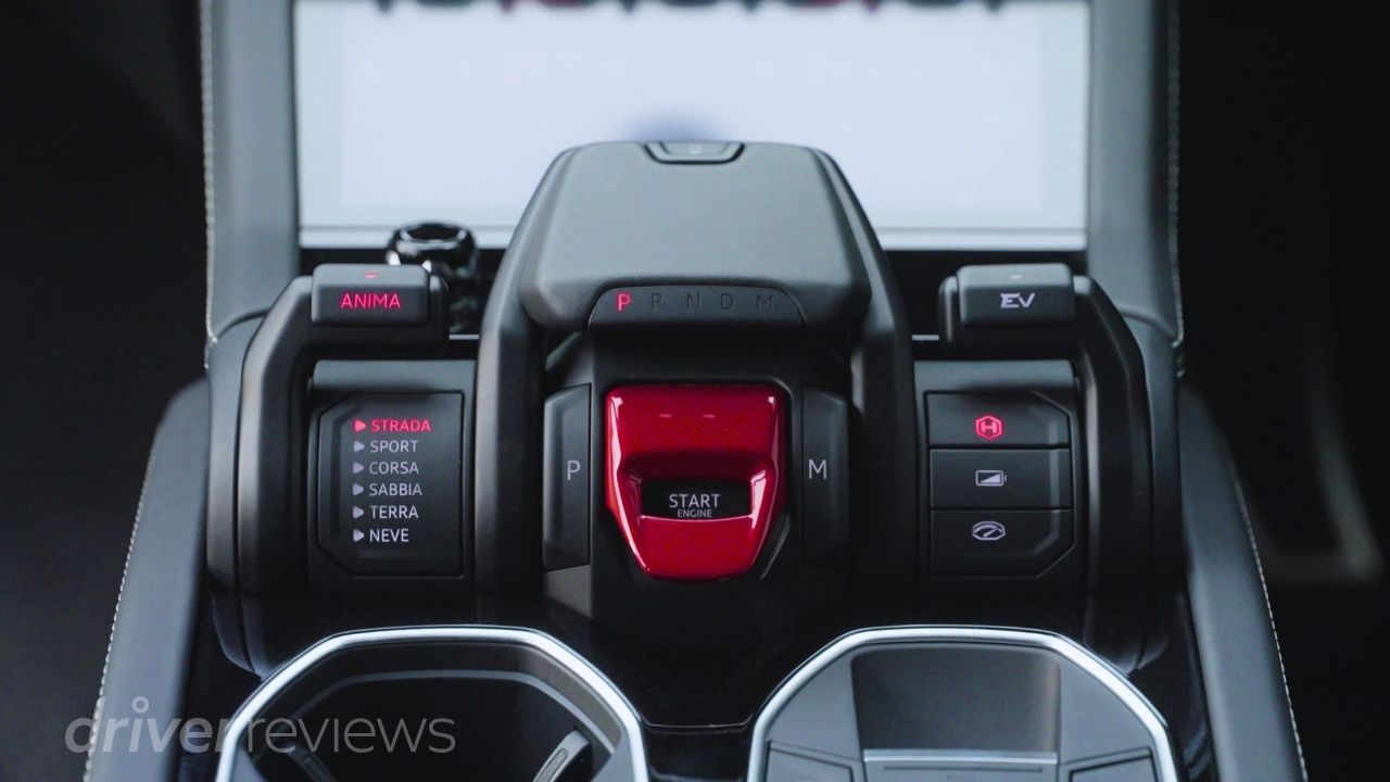 Lamborghini Urus SE Tamburo control centre showing red engine start flap, driving modes including Strada Sport Corsa Sabbia Terra Neve and EV button